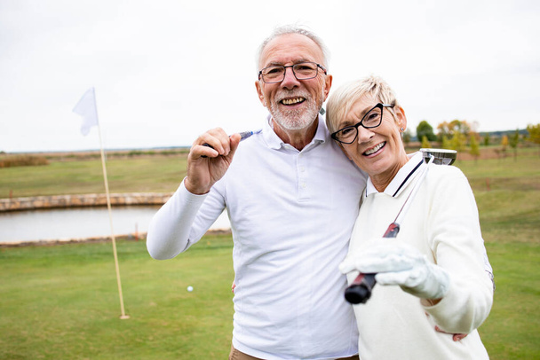 Retrato de personas mayores jubiladas con palos de golf que juegan su juego deportivo favorito y disfrutan del tiempo libre. - Foto, Imagen