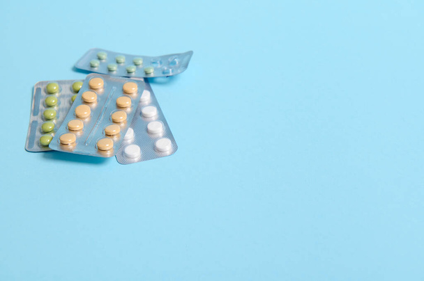 Blistr s multi-barevné lékařské pilulky na modrém pozadí s kopírovacím prostorem pro reklamu. Léky, léky, farmaceutické dragáže. Koncepce léčby a léčby různých onemocnění - Fotografie, Obrázek
