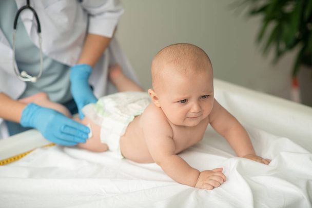 Baby wird auf eine Spritze am Oberschenkel vorbereitet - Foto, Bild