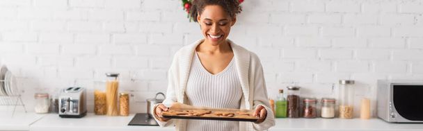 正アフリカ系アメリカ人女性を保持焼きクリスマスジンジャーブレッドでキッチン,バナー  - 写真・画像