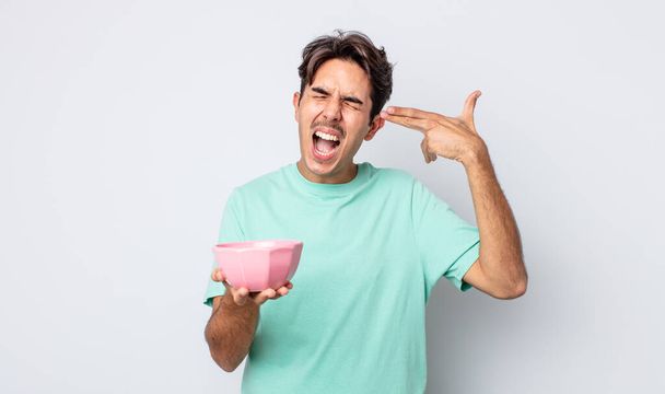 young hispanic man looking unhappy and stressed, suicide gesture making gun sign. empty bowl concept - Photo, Image