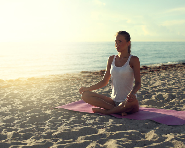 Frau macht Yoga am Strand bei Sonnenaufgang - Foto, Bild
