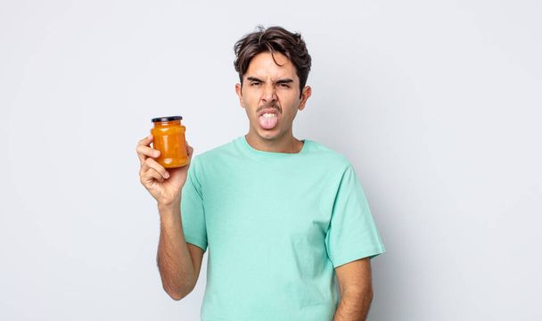 young hispanic man feeling disgusted and irritated and tongue out. peach jelly concept - Fotoğraf, Görsel