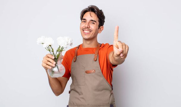 young hispanic man smiling proudly and confidently making number one. florist concept - Foto, immagini