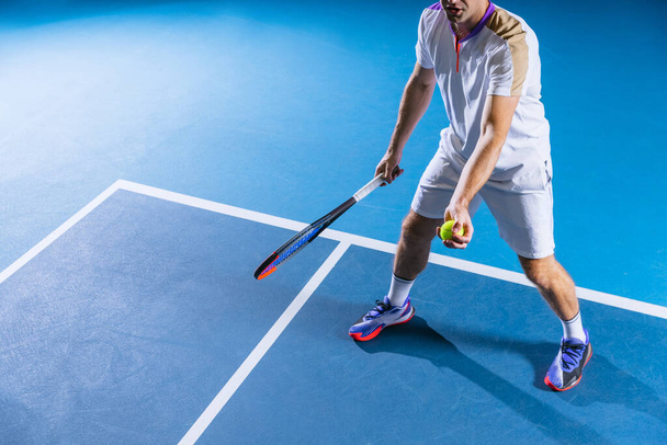 Cropped portrait of professional male tennis player training isolated over gym background - Photo, Image