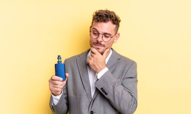 young handsome man smiling with a happy, confident expression with hand on chin. vaporizer concept - Foto, imagen