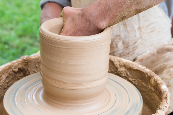 Руки людини, що робить глиняну вазу на гончарному колесі
 - Фото, зображення