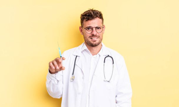young handsome man looking puzzled and confused. physician syringe concept - Φωτογραφία, εικόνα