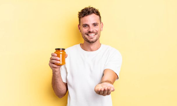 young handsome man smiling happily with friendly and  offering and showing a concept. peach jelly concept - Fotoğraf, Görsel