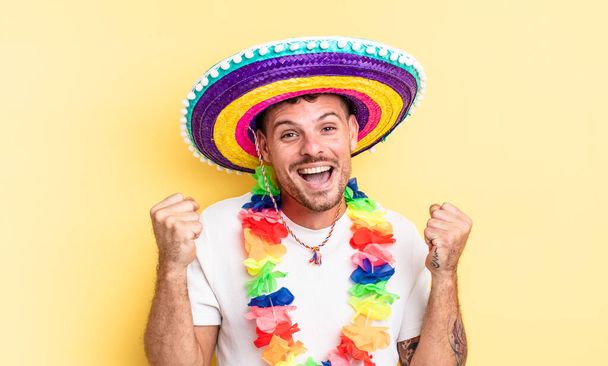 young handsome man feeling shocked,laughing and celebrating success. mexican party concept - Fotografie, Obrázek