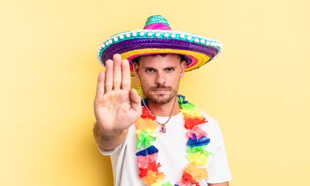 young handsome man looking serious showing open palm making stop gesture. mexican party concept - Foto, immagini