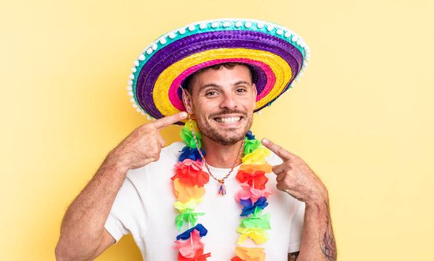 young handsome man smiling confidently pointing to own broad smile. mexican party concept - Fotoğraf, Görsel