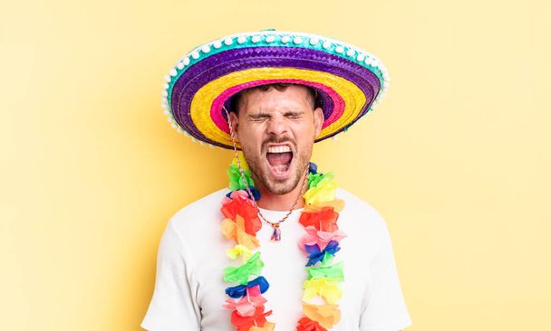young handsome man shouting aggressively, looking very angry. mexican party concept - Foto, Imagen