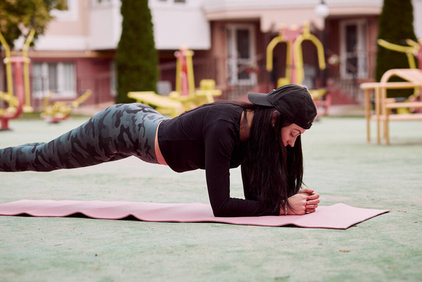 Mujer joven con equipo haciendo ejercicio afuera. Entrenamientos al aire libre. Concepto de estilo de vida saludable. Haciendo tablón. Foto de alta calidad - Foto, imagen