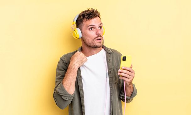 young handsome man feeling stressed, anxious, tired and frustrated headphones and smartphone concept - Photo, image