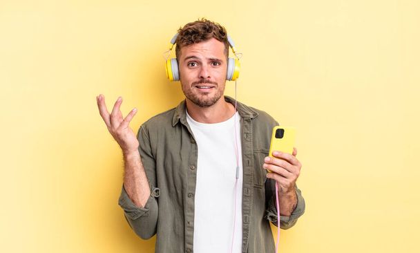 young handsome man feeling happy, surprised realizing a solution or idea headphones and smartphone concept - Valokuva, kuva