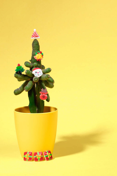 Cactus decorated with small Xmas symbols as alternative Xmas tree on yellow. Vertical orientation. - Φωτογραφία, εικόνα