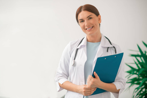 Femme aux cheveux bruns médecin en robe blanche assis au bureau des médecins - Photo, image