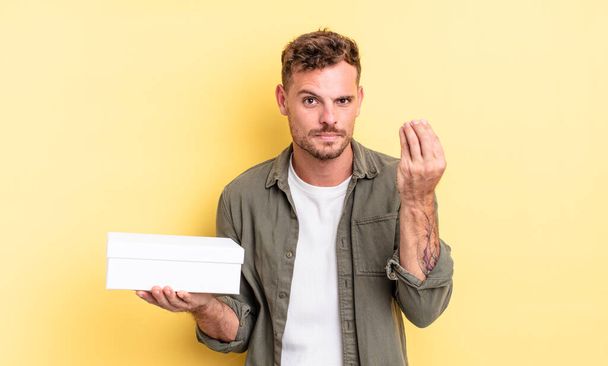 young handsome man making capice or money gesture, telling you to pay. white box concept - Fotoğraf, Görsel