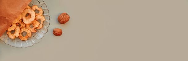 Kuivatut viipaloidut omenalastut paperipussissa ja saksanpähkinöissä - terveellisiä välipaloja. Oikea ravitsemus, terveellinen ruoka käsite. Huippunäkymä. Erittäin leveä lippu. Laadukas kuva - Valokuva, kuva