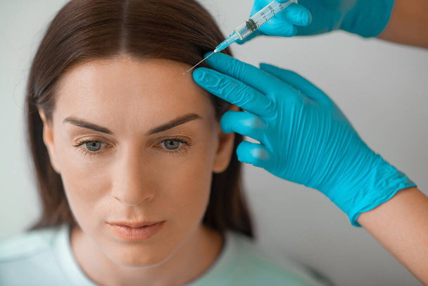 Uma mulher de cabelos escuros de meia idade com um procedimento de injeções espancadas - Foto, Imagem