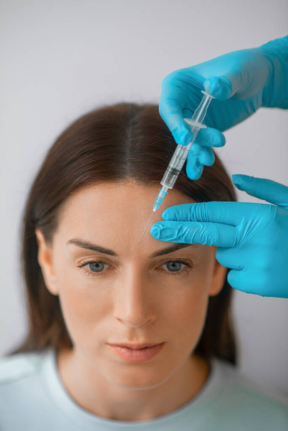 A dark-haired mid aged woman having a beaty injections procedure - Foto, imagen