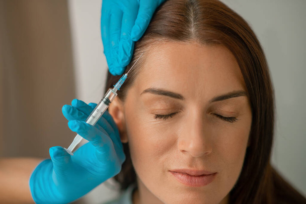 Cosmetoloog injecteren collageen aan haar klanten gezicht - Foto, afbeelding