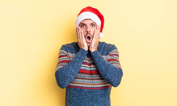 young handsome man feeling shocked and scared. christmas concept - Foto, Imagen