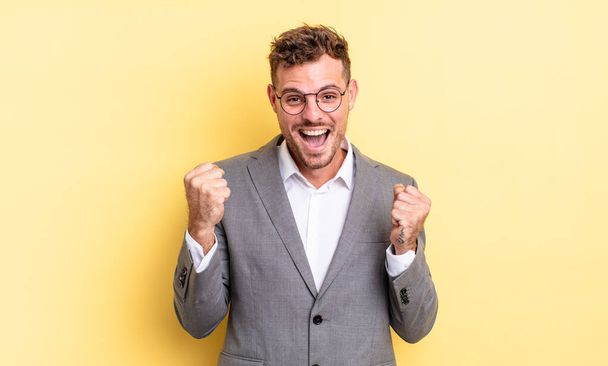 young handsome man feeling shocked,laughing and celebrating success. business concept - Photo, Image
