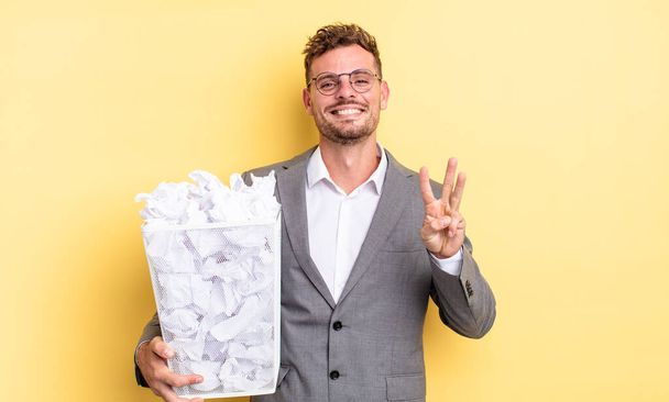 young handsome man smiling and looking friendly, showing number three paper balls trash concept - Фото, изображение
