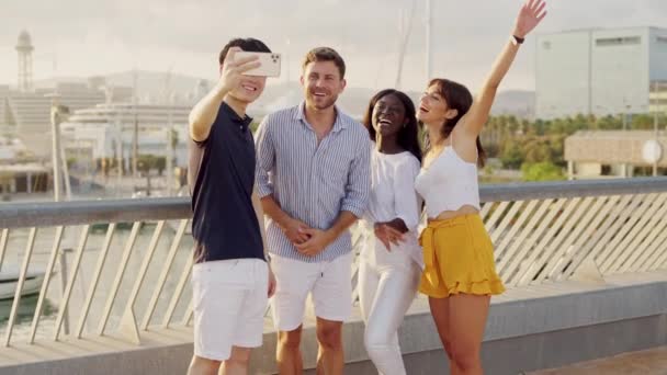 Happy multi-ethnic friends making selfie on smartphone while standing in seaport outdoors - Footage, Video