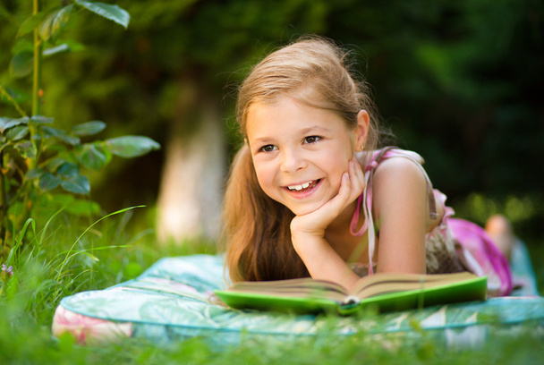 Little girl is reading a book outdoors - Fotoğraf, Görsel