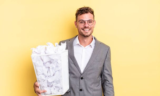 young handsome man looking happy and pleasantly surprised paper balls trash concept - Foto, immagini
