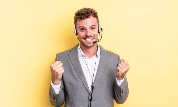 young handsome man feeling shocked,laughing and celebrating success. telemarketer concetp - 写真・画像