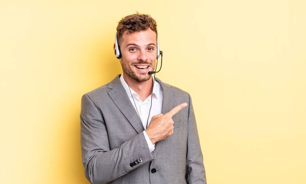 young handsome man looking excited and surprised pointing to the side. telemarketer concetp - Foto, Imagem