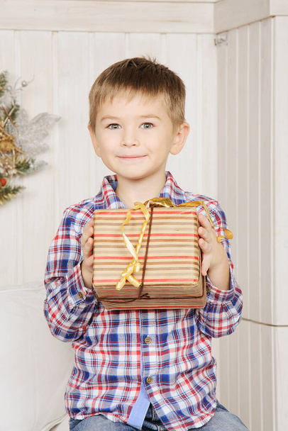Noel hediyesini elinde tutan sevimli çocuk şaşırmış bir şekilde gülümsedi.. - Fotoğraf, Görsel