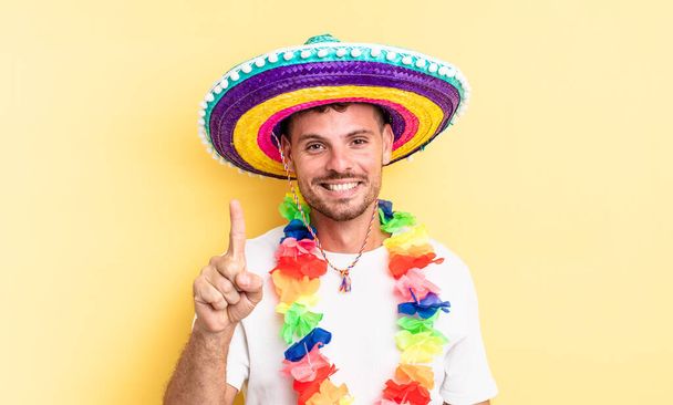 young handsome man smiling and looking friendly, showing number one. mexican party concept - Valokuva, kuva