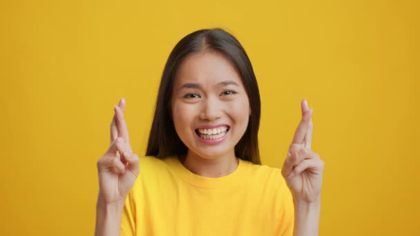 Asyalı Kadın Parmaklarını çapraz yapıp Sarı Arkaplanda Şans İstiyor - Video, Çekim