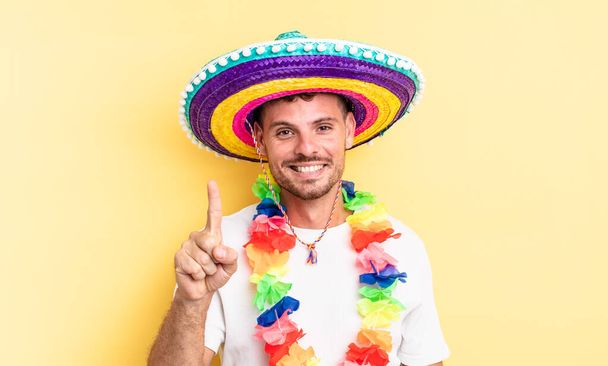 young handsome man smiling and looking friendly, showing number one. mexican party concept - Foto, imagen