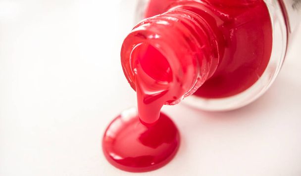 kaatamalla punainen kynsilakka pullosta valkoisella taustalla - Valokuva, kuva