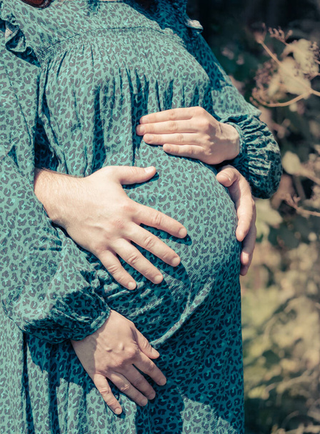 El hombre abraza a la mujer embarazada por detrás por el vientre. - Foto, Imagen