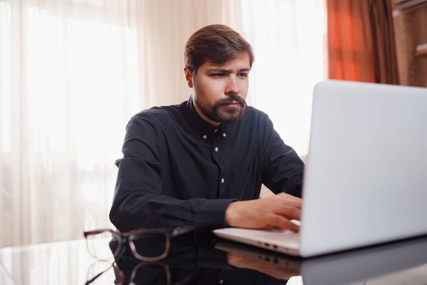 Hombre joven guapo usando ordenador portátil en casa. - Foto, Imagen