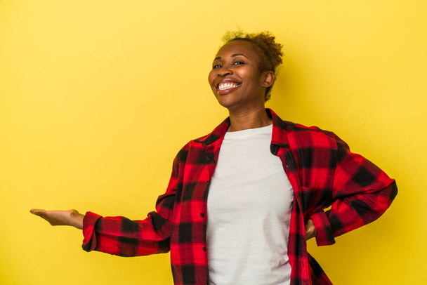 Junge afrikanisch-amerikanische Frau isoliert auf gelbem Hintergrund mit einem Willkommensausdruck. - Foto, Bild
