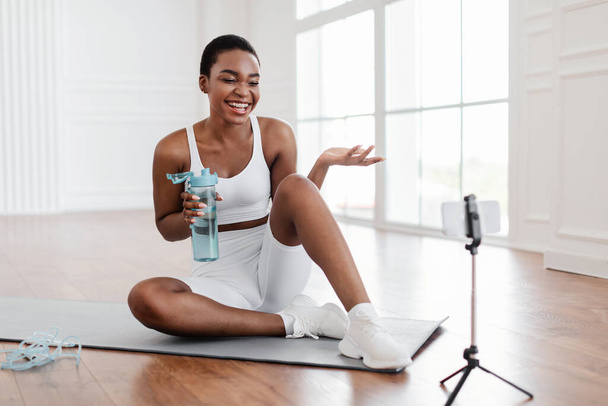 Young black woman woman talking with online trainer using cellphone - Photo, Image