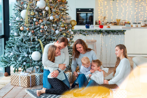 Happy family with four sibilings near the Christmas tree with the present boxes. Christmas family morning, christmas mood concept - Фото, зображення