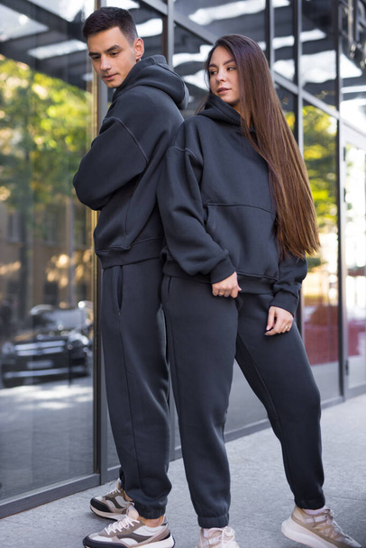 Stylish couple in pair costumes posing near building - Фото, изображение