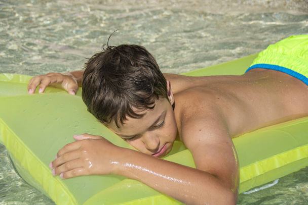 Młody chłopiec relaksujący się na dmuchanym materacu w morzu - Zdjęcie, obraz