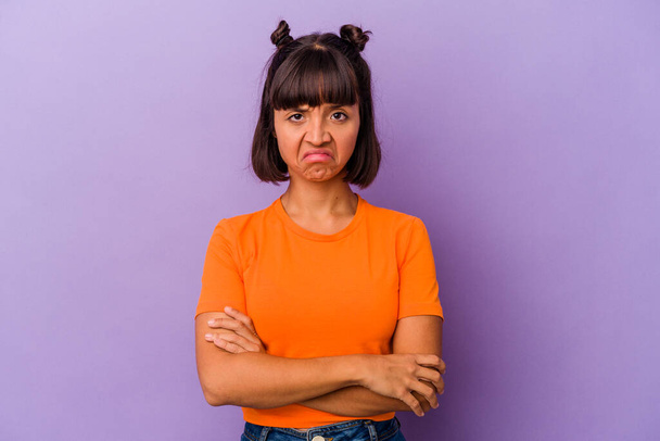 Young mixed race woman isolated on purple background frowning face in displeasure, keeps arms folded. - Photo, Image