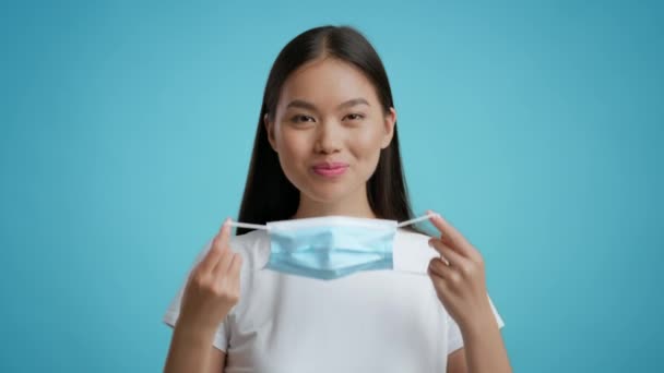 保護顔マスクを着用する幸せな韓国人女性,青の背景 - 映像、動画