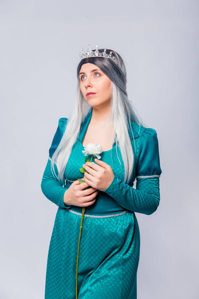 Portrait of a princess in a medieval, fantasy, turquoise dress with ash hair and a silver crown, posing with white roses in hands, isolated on a white background. - Photo, Image